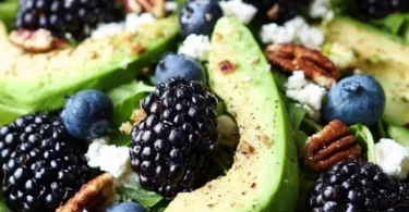 Delicious blackberry avocado salad topped with fresh greens and dressing