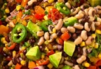 A bowl of colorful cowboy caviar with black beans, corn, and tomatoes