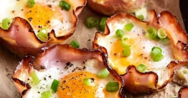 Baked ham and cheese egg cups served on a plate, garnished with herbs.