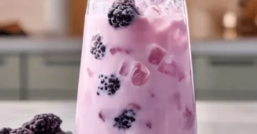 Homemade blackberry coconut pink drink served in a glass with berries