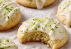 Freshly baked Key Lime Cookies on a cooling rack with vibrant lime slices