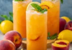 Glass of refreshing Peach Lemonade with slices of peach and lemon