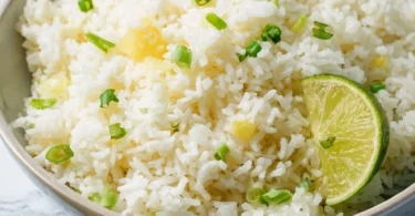 Delicious Pineapple Rice served in a bowl with fresh pineapple chunks and herbs.
