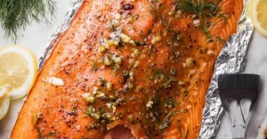 Plate of delicious smoked salmon garnished with herbs and lemon slices
