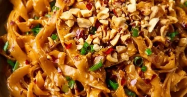 Spicy peanut butter noodles served in a bowl with fresh vegetables